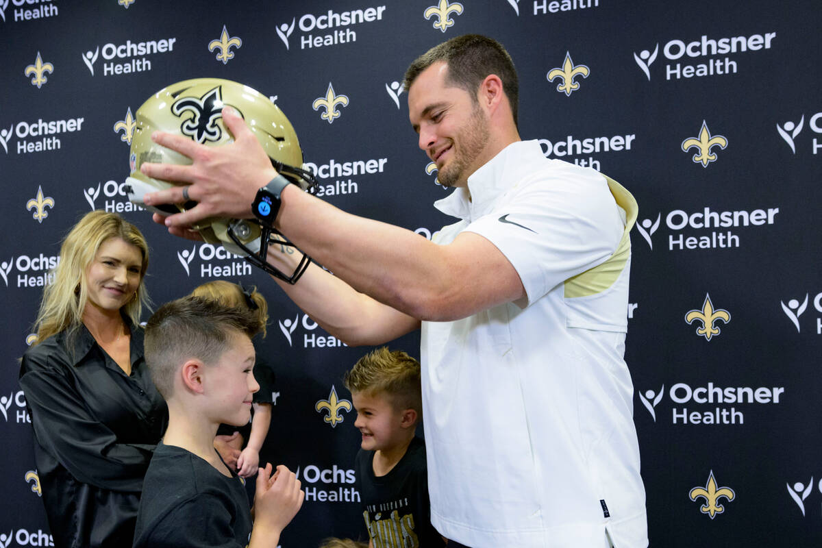 Derek Carr puts a Saints helmet on his son, Dallas Carr, as his wife Heather Carr, left, and ot ...