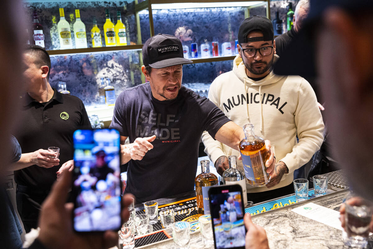 Mark Wahlberg, center, pours drinks at the bar during the opening celebration of a new Wahlburg ...