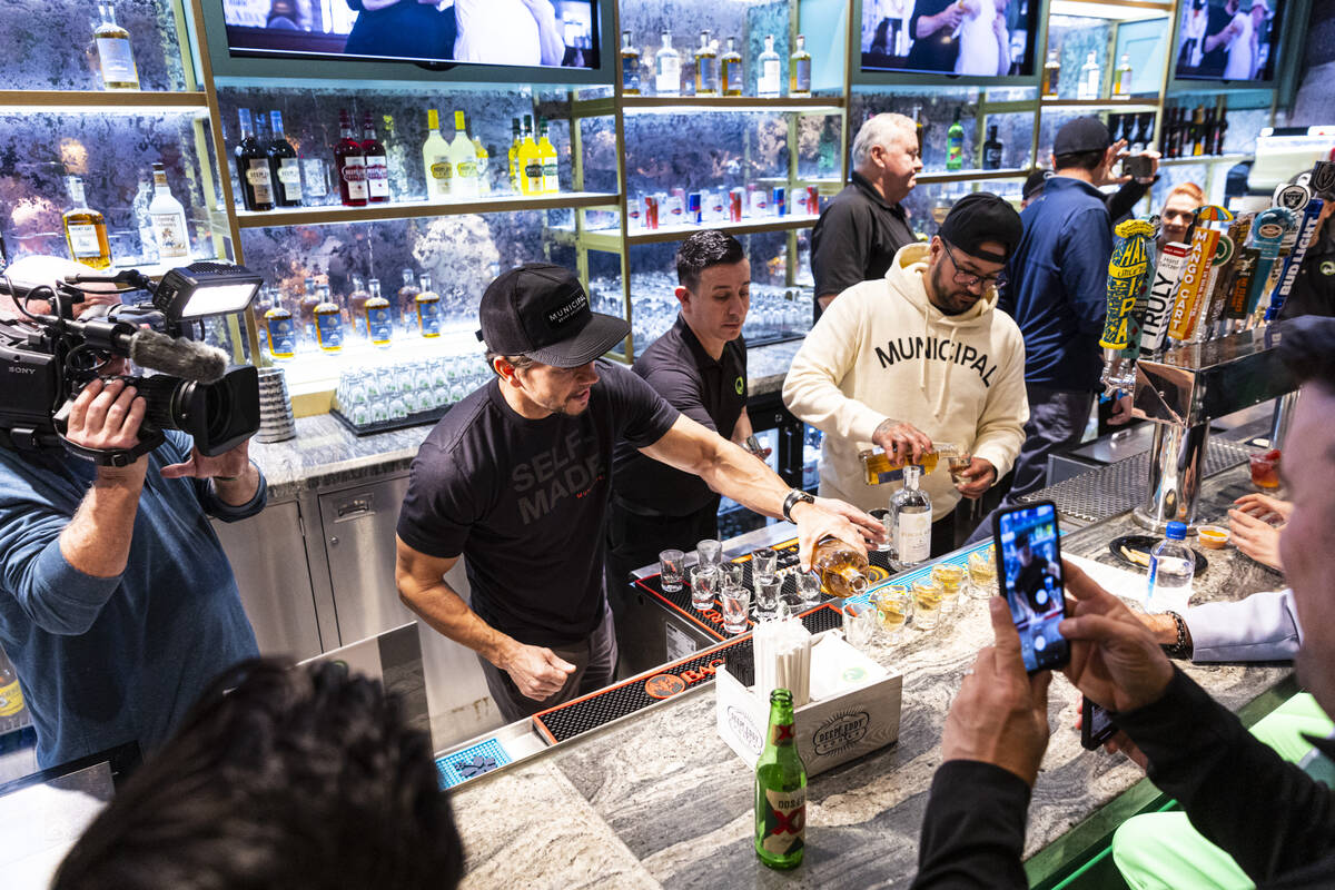 Mark Wahlberg, left, pours drinks at the bar during the opening celebration of a new Wahlburger ...