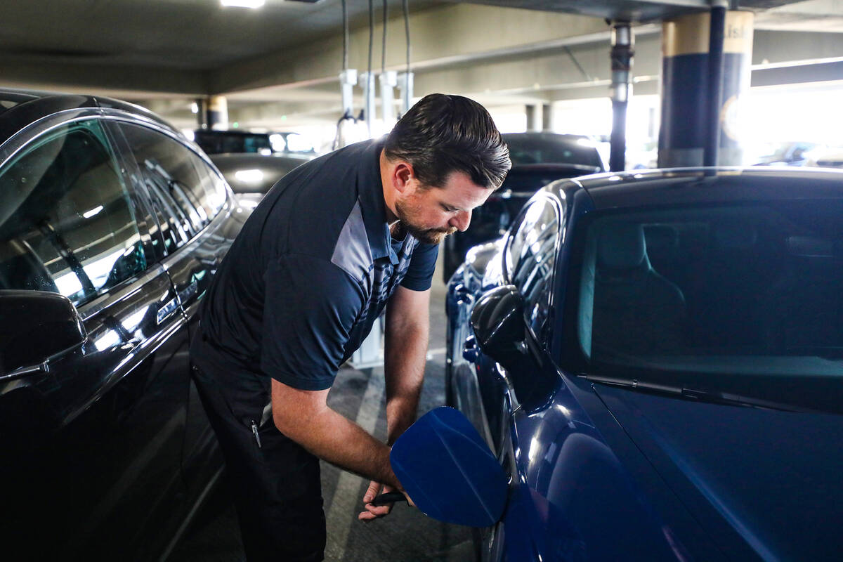 Andrew Pluta, valet manager, plugs in an electric vehicle to charge at Harry Reid International ...