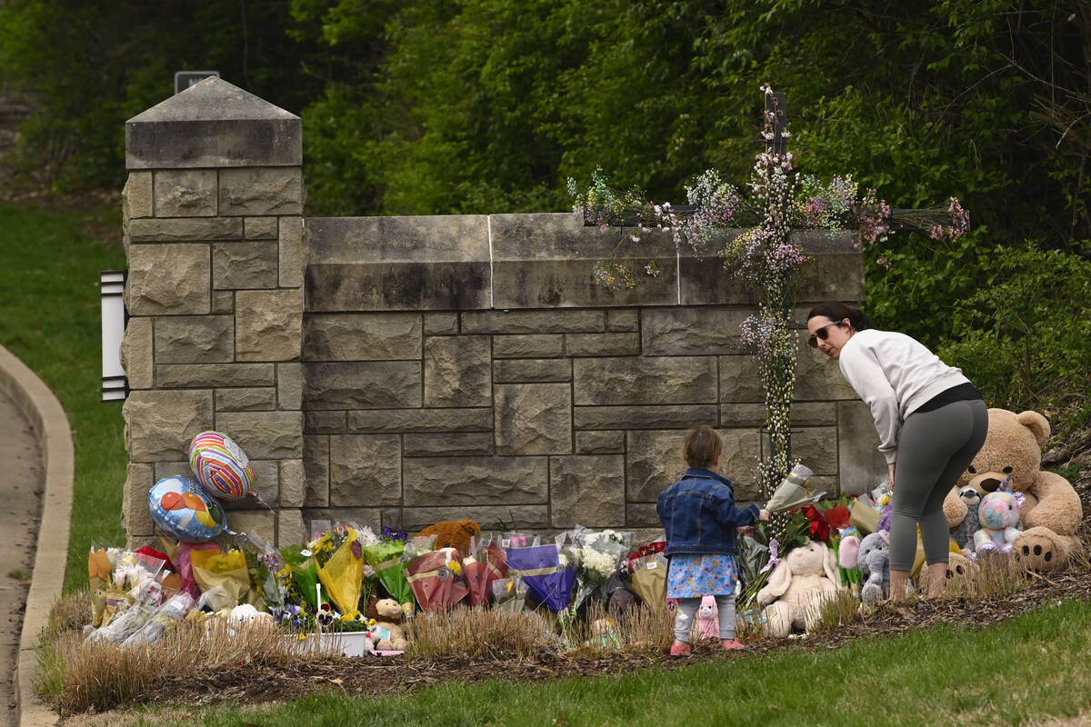A woman and child bring flowers to lay at the entry to Covenant School which has becomes a memo ...