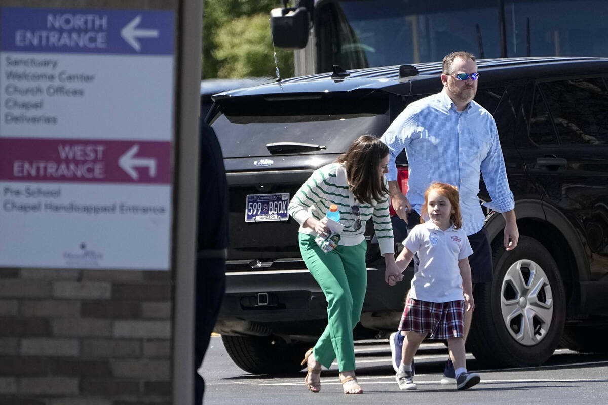 Adults walk with a child at a reunification center at the Woodmont Baptist Church after a shoot ...