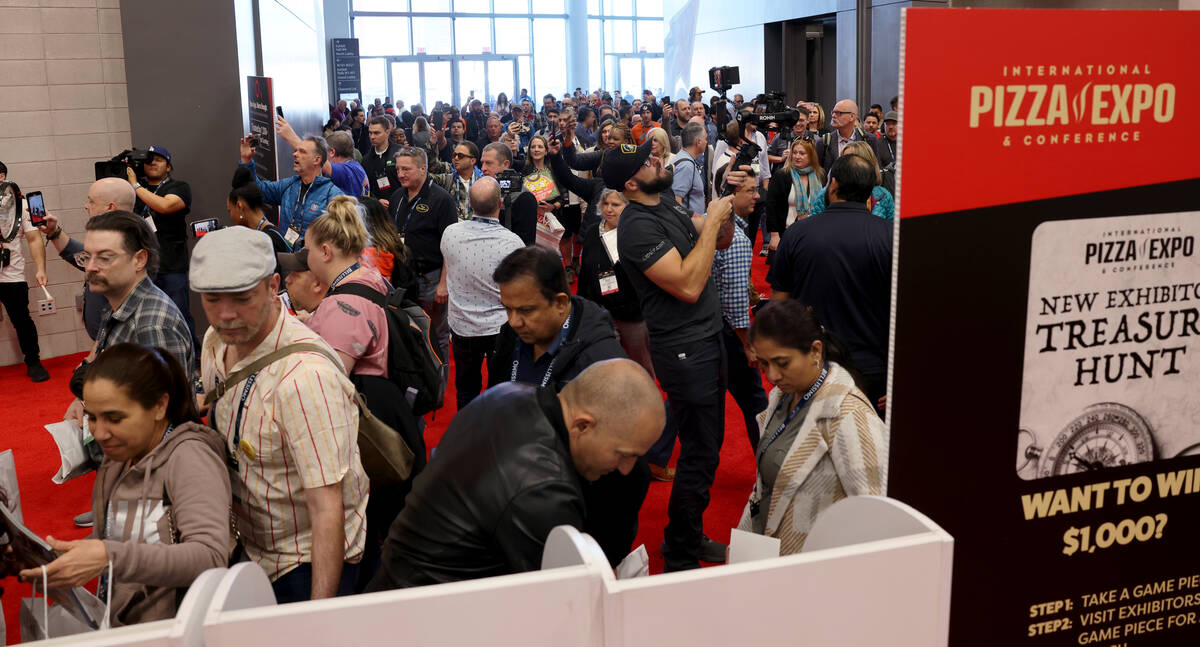 Conventioneers arrive and grab publications at the opening of the show floor at the Internation ...