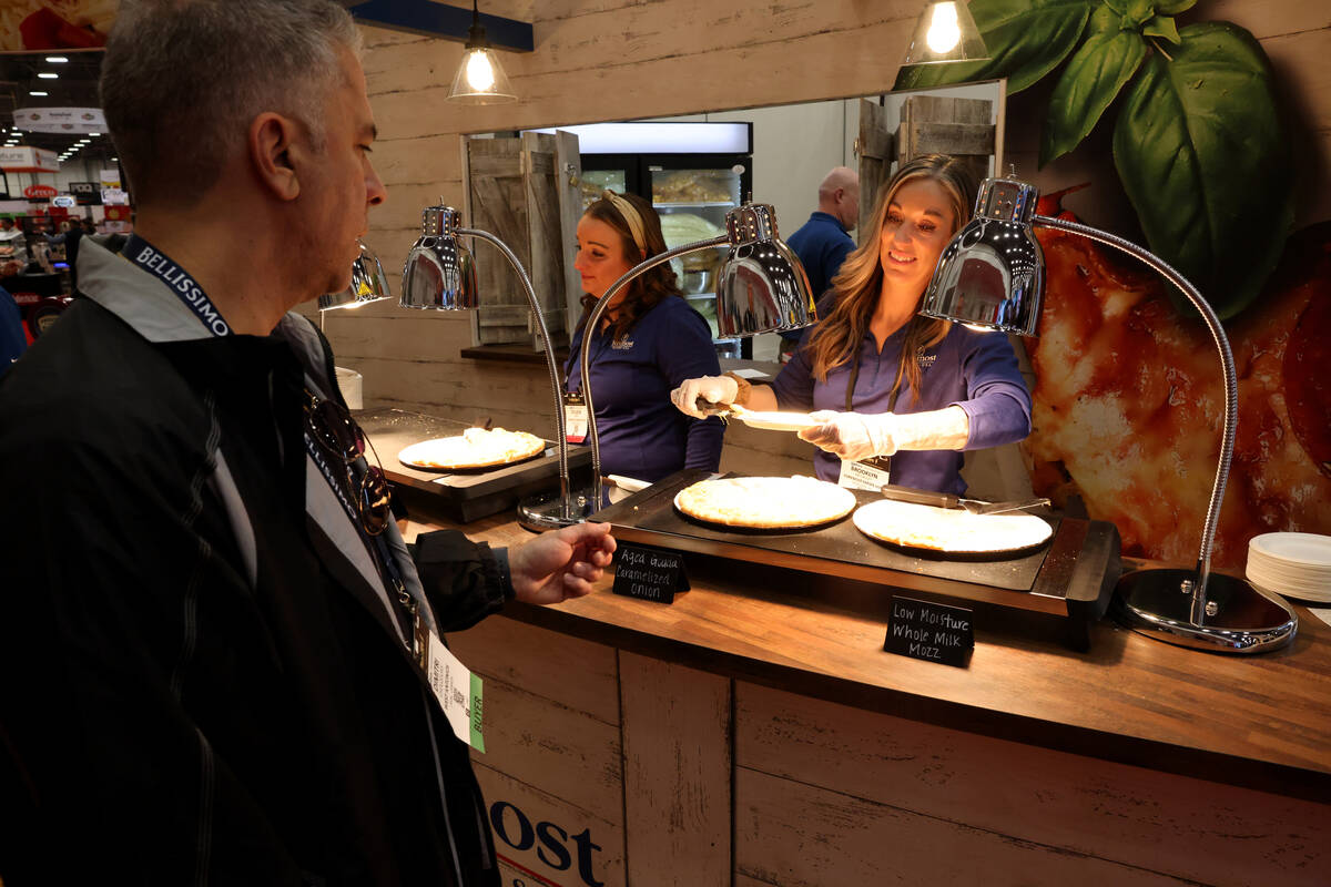 Brooklyn McCauley of Foremost Farms offers a pizza sample to Dimitri Chouzouris of Canada at th ...