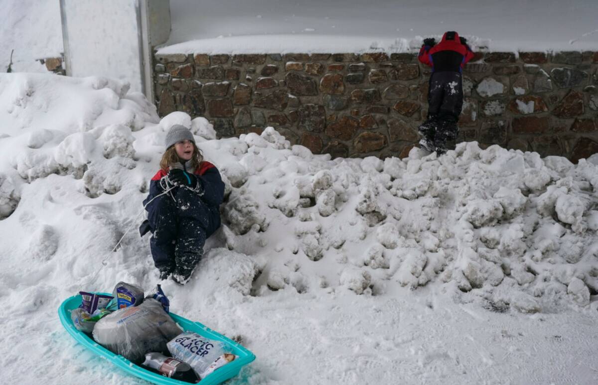 Abigail Apgar, 10, whose family car is buried in the snow, takes a break while helping her pare ...