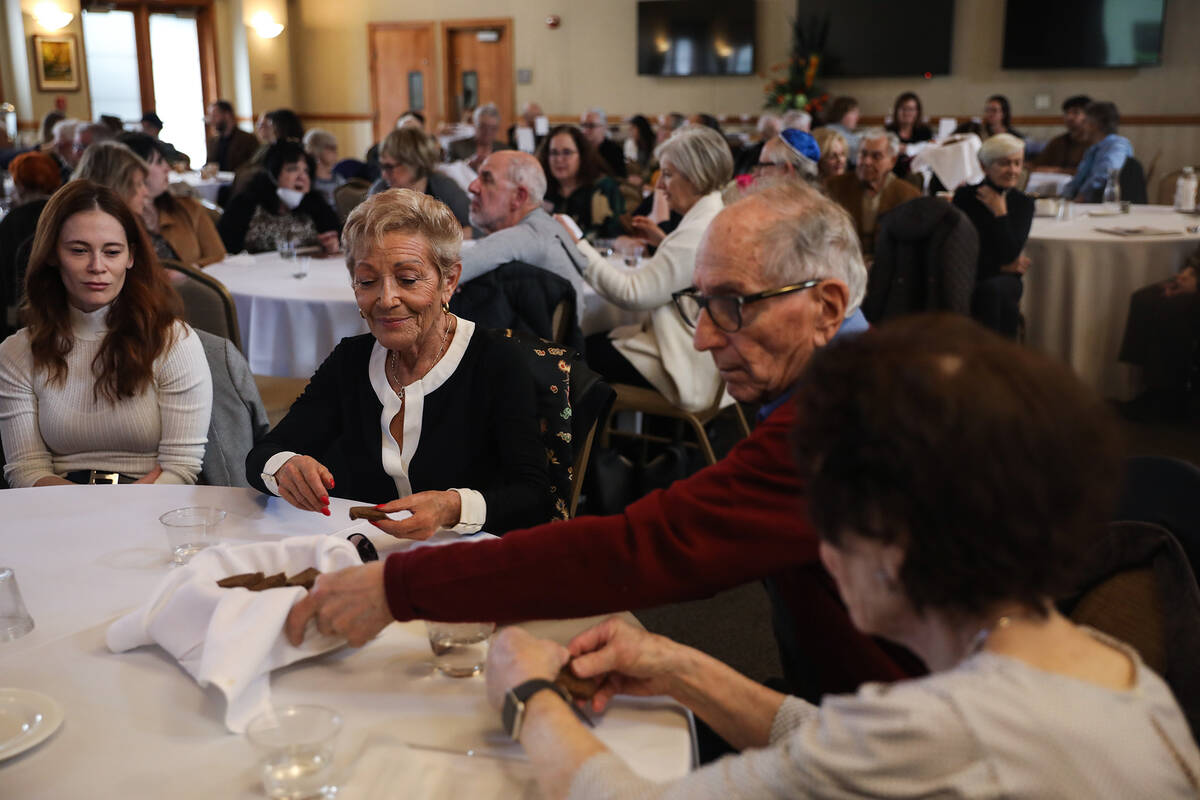 Jackie Beer, center, grabs matzah bread next to Phillip Fiol during a Seder Passover meal at th ...
