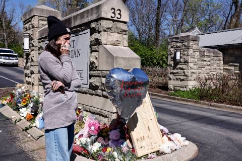 A woman wipes away tears as she visits a memorial at the entrance to The Covenant School on Wed ...