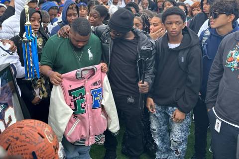 Jeremiah Wiggins, 35, center, has an arm around Quan Britton, 23, at a vigil for Omarion Wilson ...