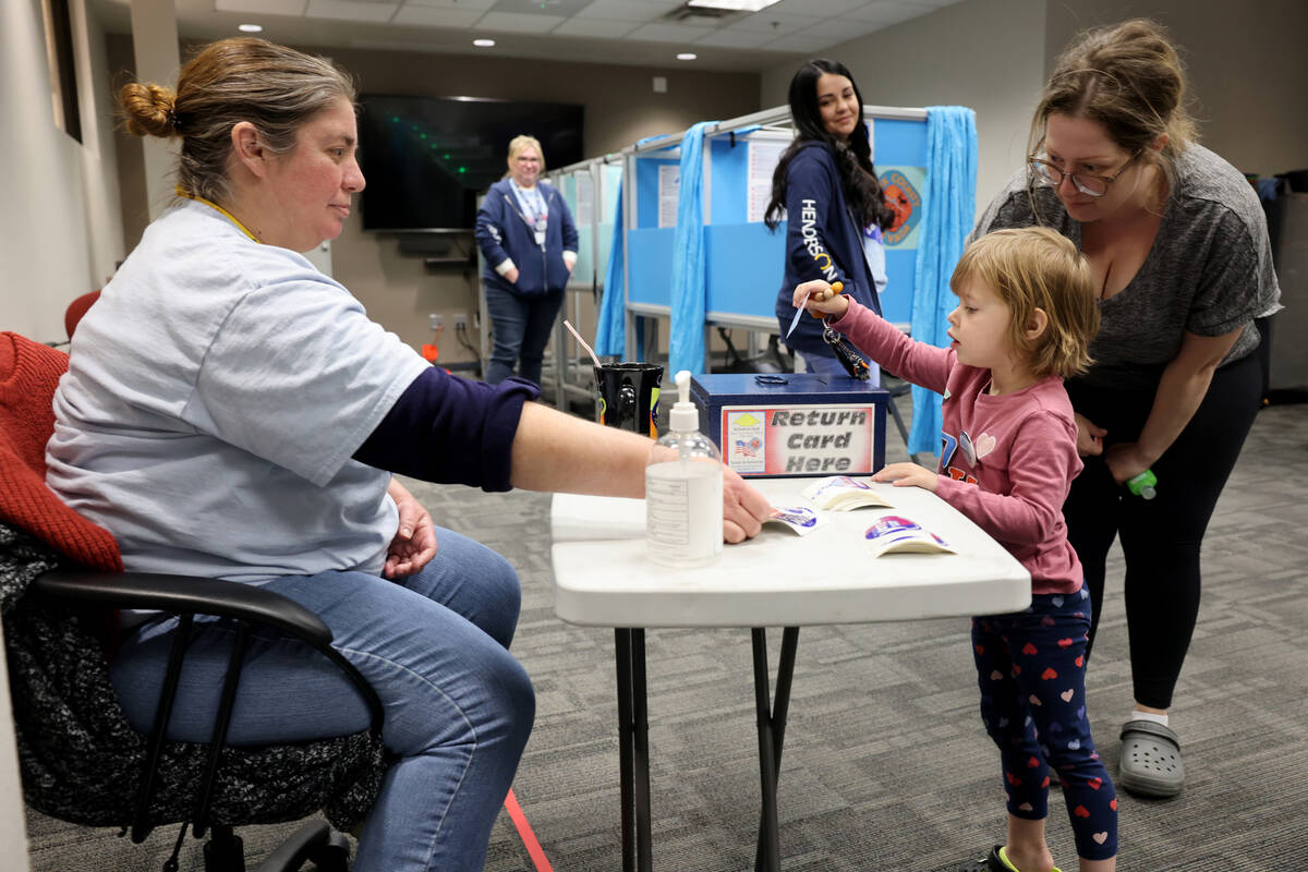 Shea Bishop, left, and her daughter Iris, 3, submit their activation card after voting at Hende ...