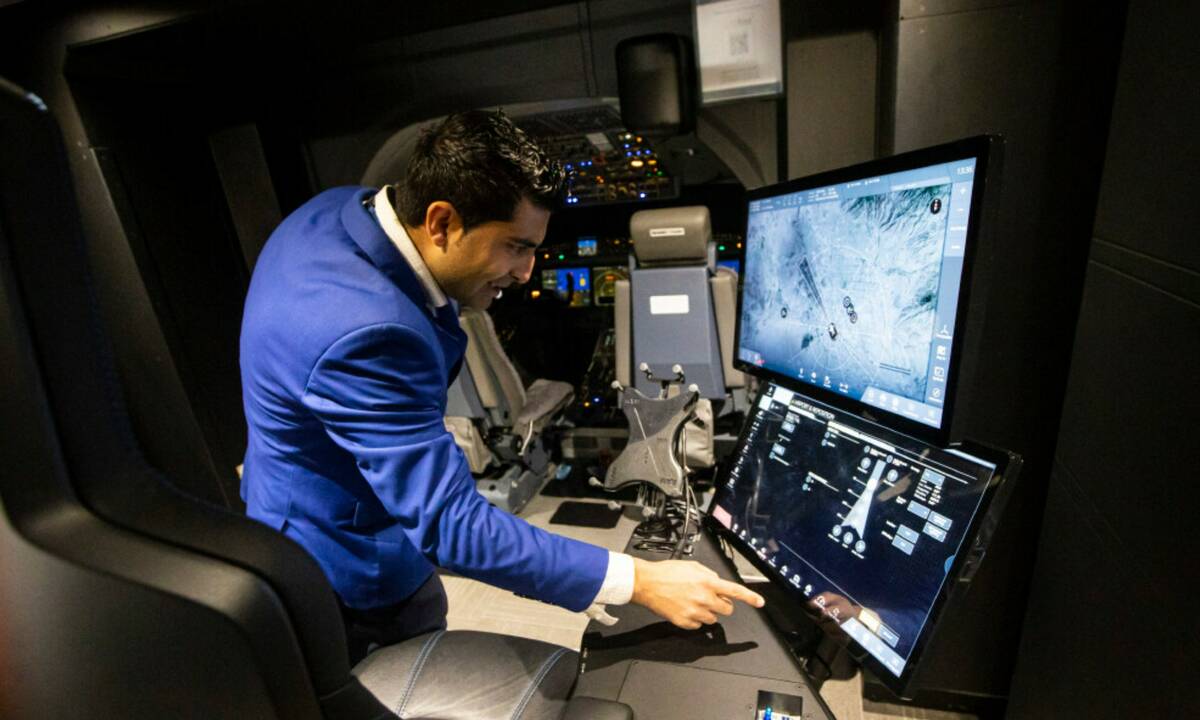 Arash Sadegh, training manager at CAE, right, turns on one of the full-flight simulators at CAE ...
