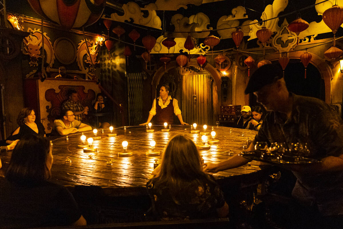 Drinks are passed out as William Bradshaw, center, performs during the The Seance Room at Lost ...