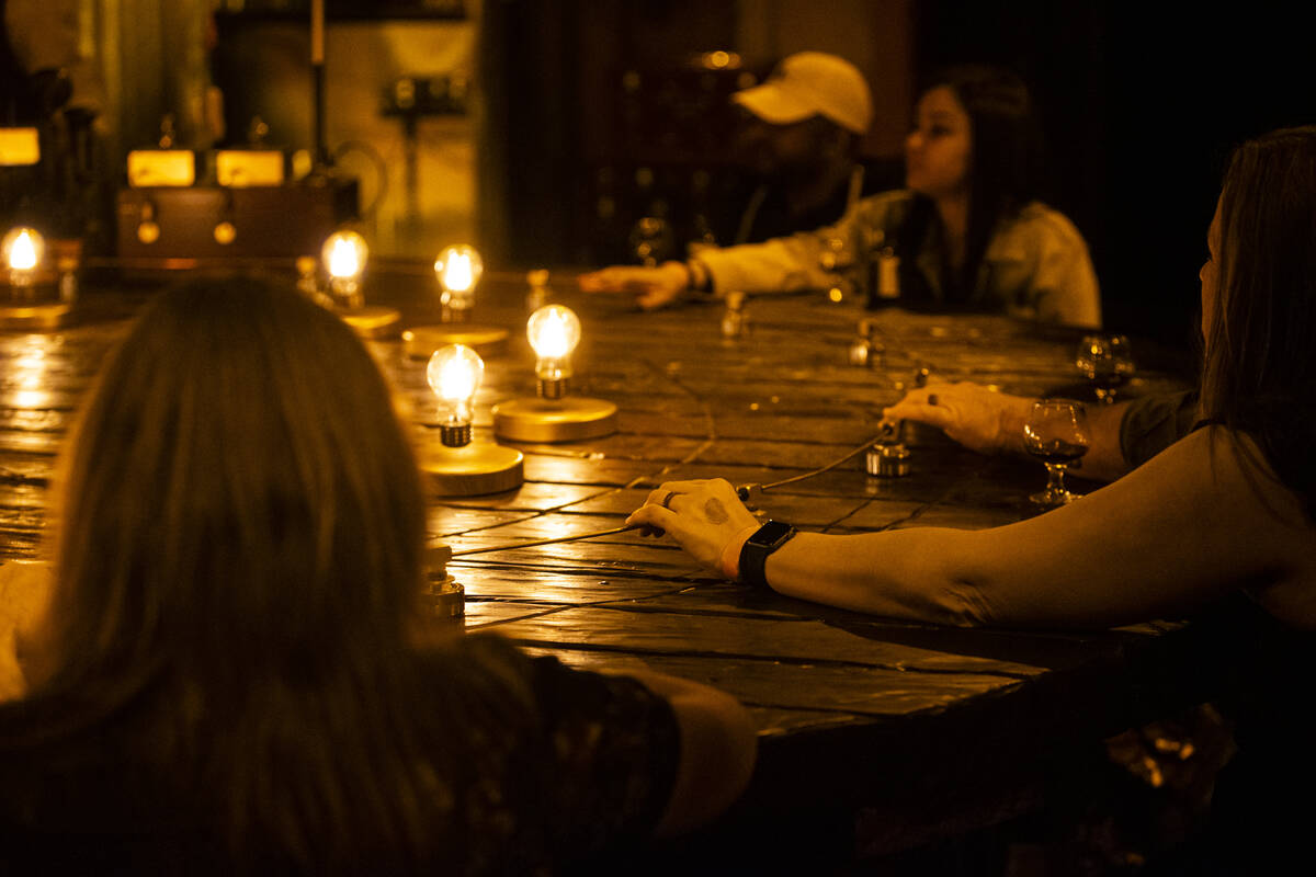 Guests hold onto a copper wire during the The Seance Room at Lost Spirits Distillery on Sunday, ...