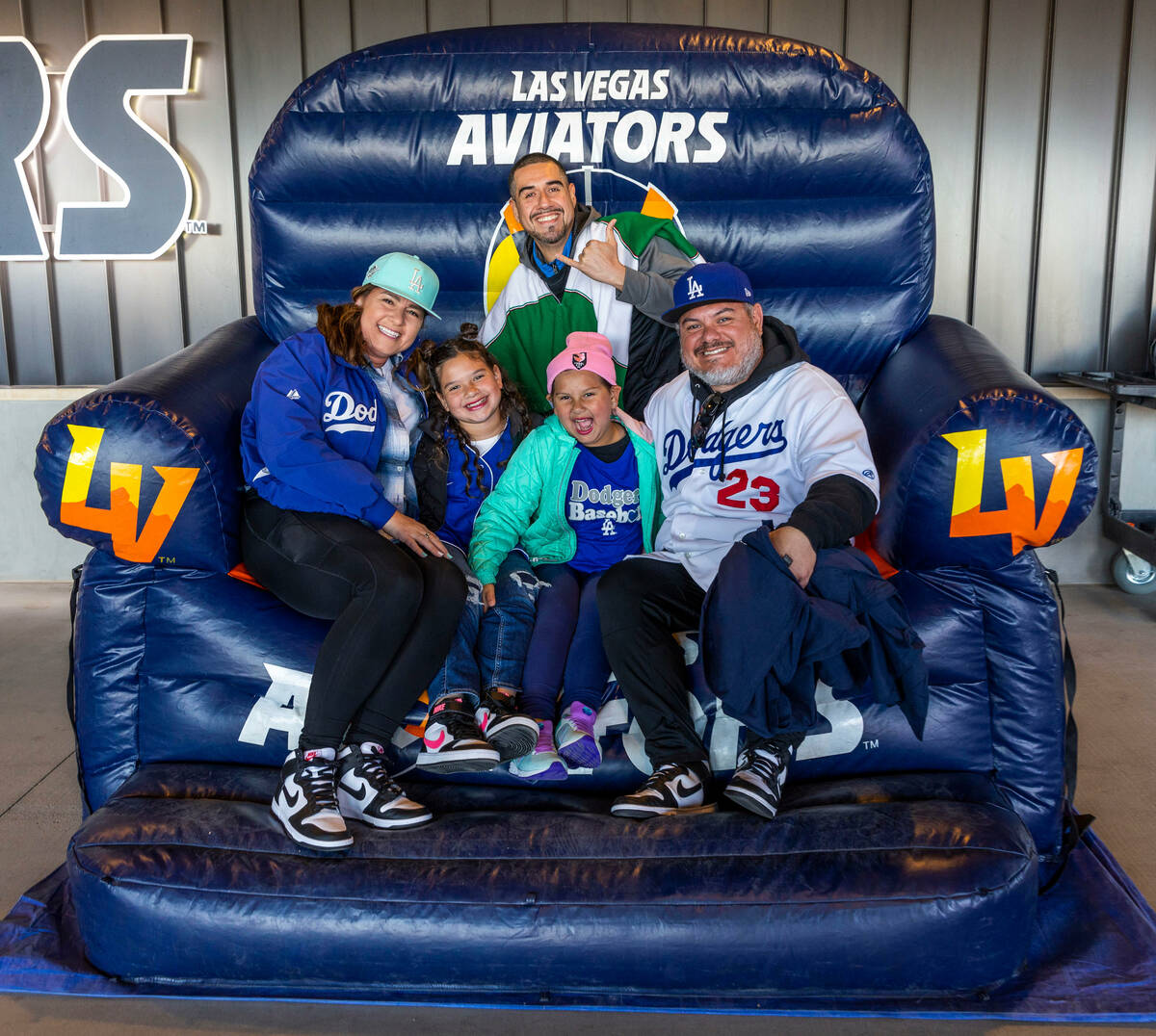 The Ortiz family take a turn in the giant chair before the first inning of the Aviators against ...