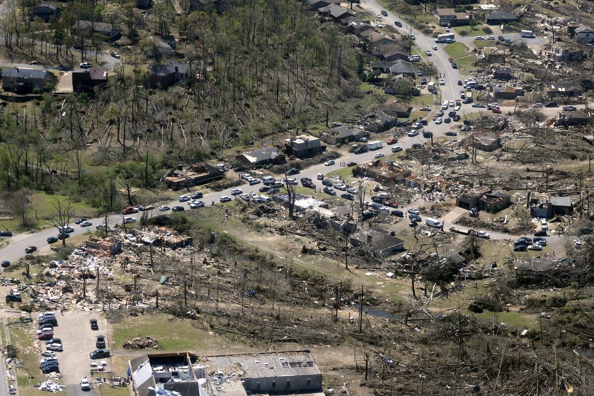 Cars line up along the road as cleanup continues from Friday's tornado damage, Sunday, April 2, ...