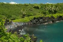 People spend time on the black sand beach at Waianapanapa State Park in Hana, Hawaii, in 2014. ...