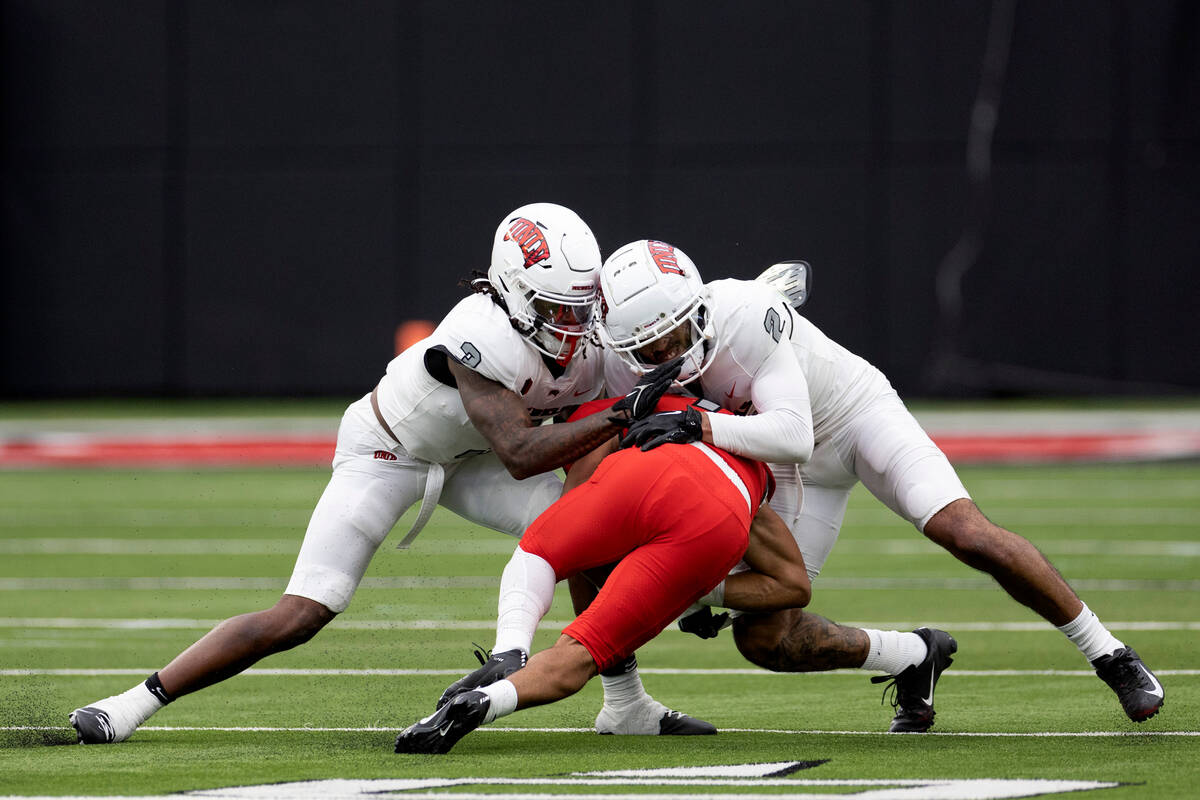 Defensive backs Johnathan Baldwin (3) and Jaxen Turner (2) tackle wide receiver Jacob De Jesus ...
