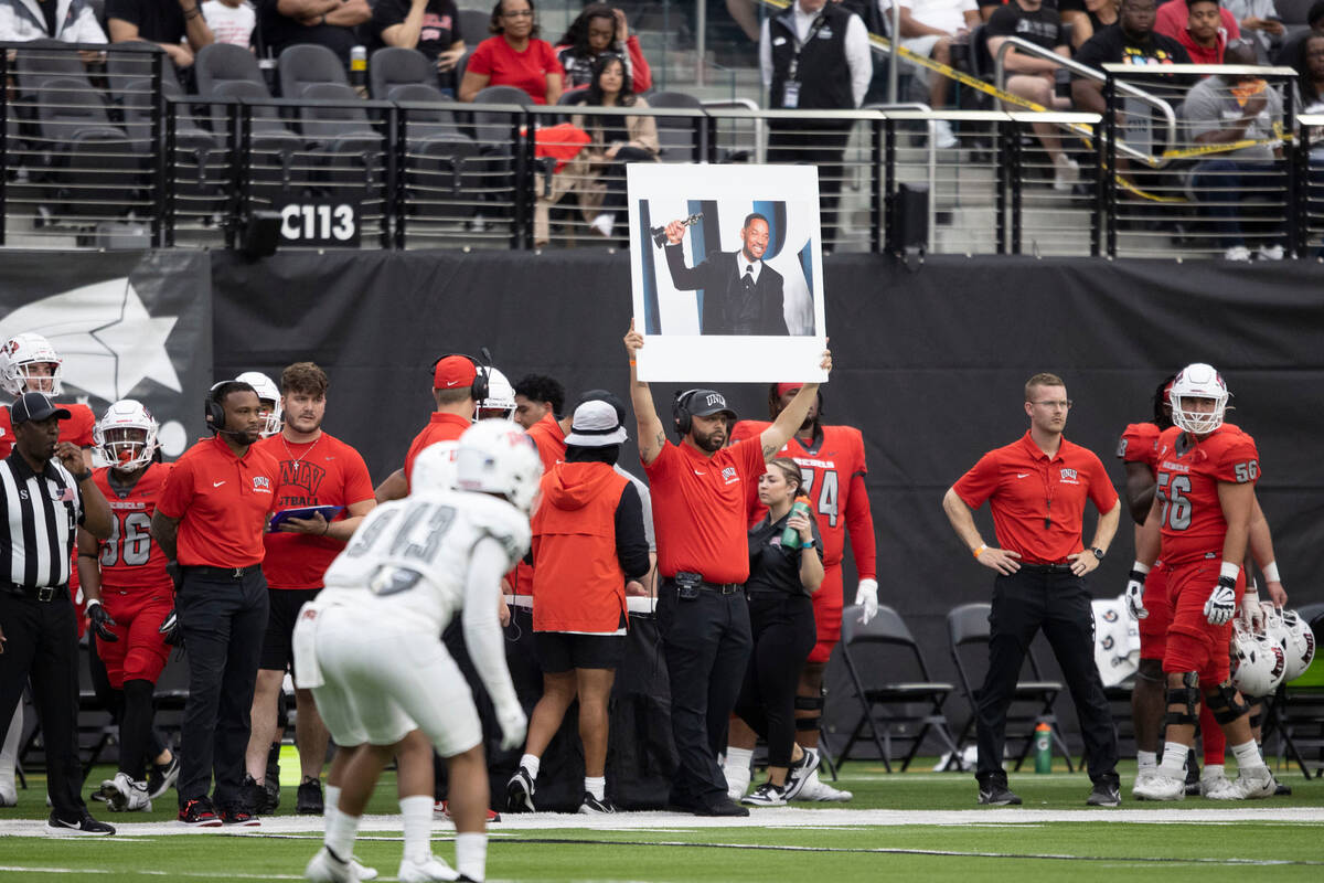 A UNLV assistant holds up a poster board of actor Will Smith to reflect the play call during th ...