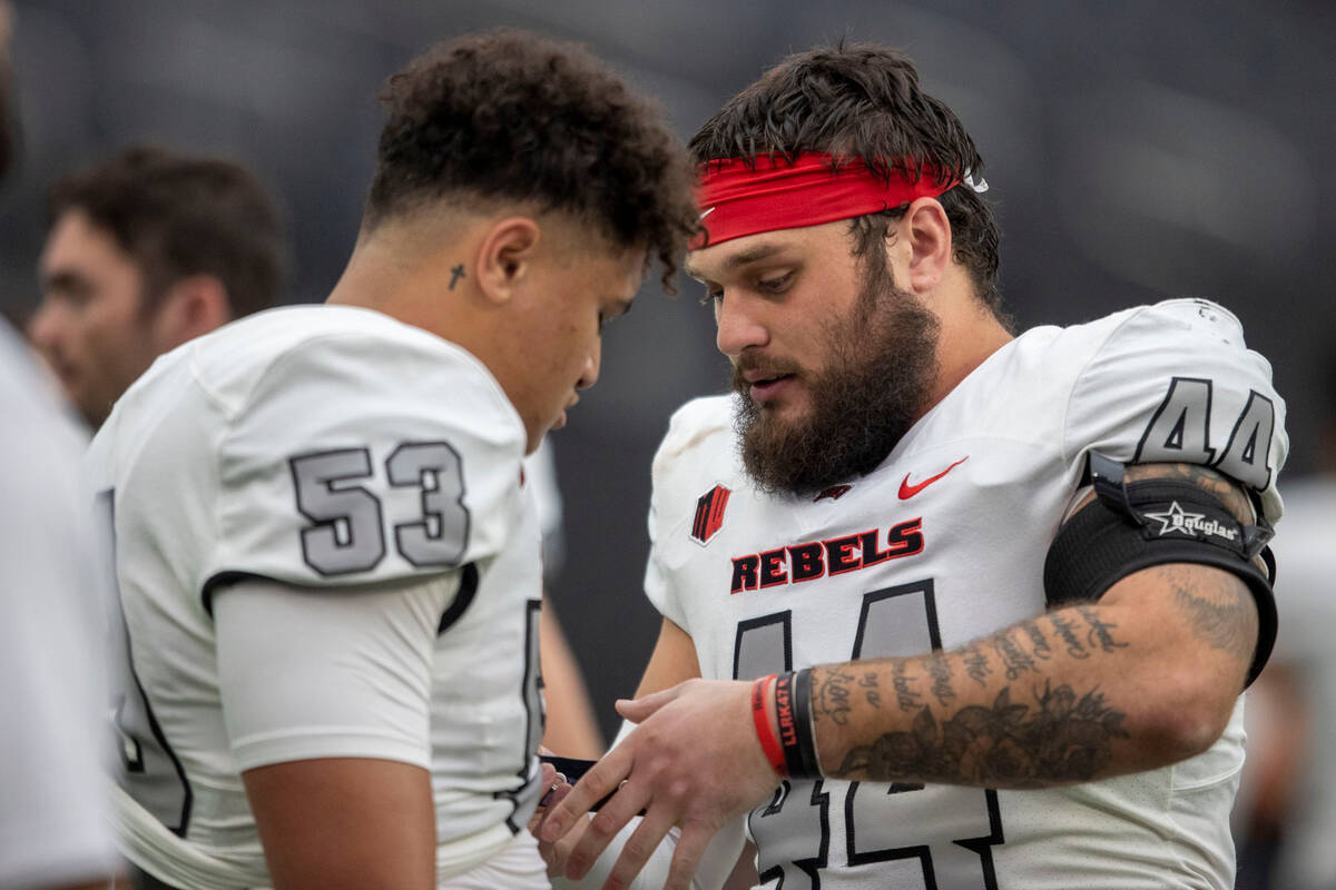 UNLV linebacker Kyle Beaudry (44) helps adjust Blessing Alualu-Tuiolemotu’s (53) uniform ...