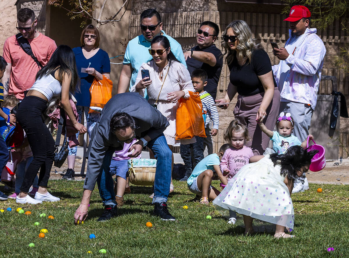 A parent gets involved as children ages 1-3 start their egg hunt during the annual Spring Carni ...
