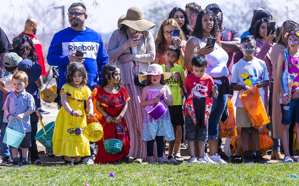 Parents and children ages 4-7 gather around a field for the next egg hunt to start during the a ...