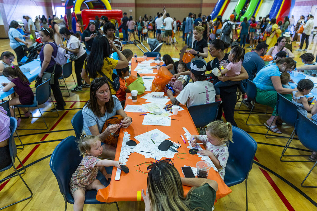Children and adults color hats and pages during the annual Spring Carnival at the Whitney Ranch ...
