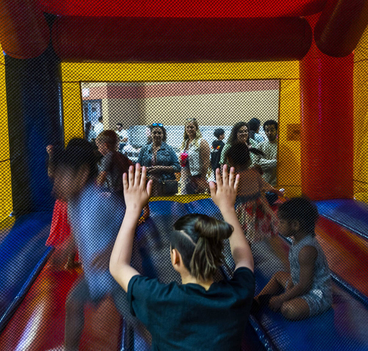 Kids enjoy a bounce house as parents look on during the annual Spring Carnival at the Whitney R ...