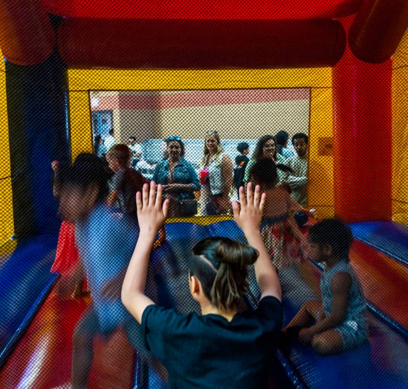 Kids enjoy a bounce house as parents look on during the annual Spring Carnival at the Whitney R ...