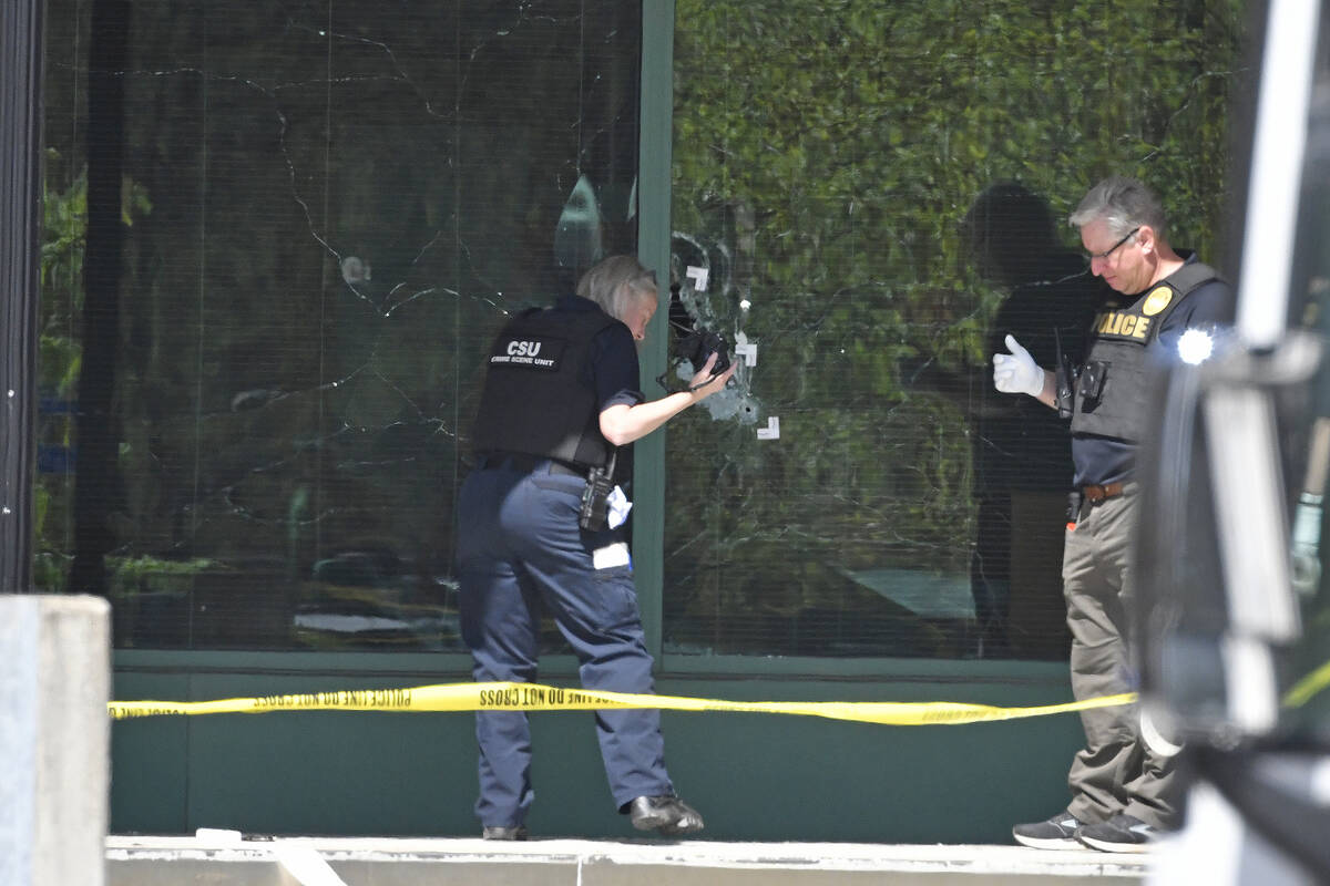 A Louisville Metro Police technician photographs bullet holes in the front glass of the Old Nat ...
