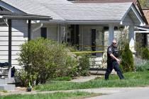A Louisville Metro Police officer walks outside of the home of the suspected shooter in the Cam ...