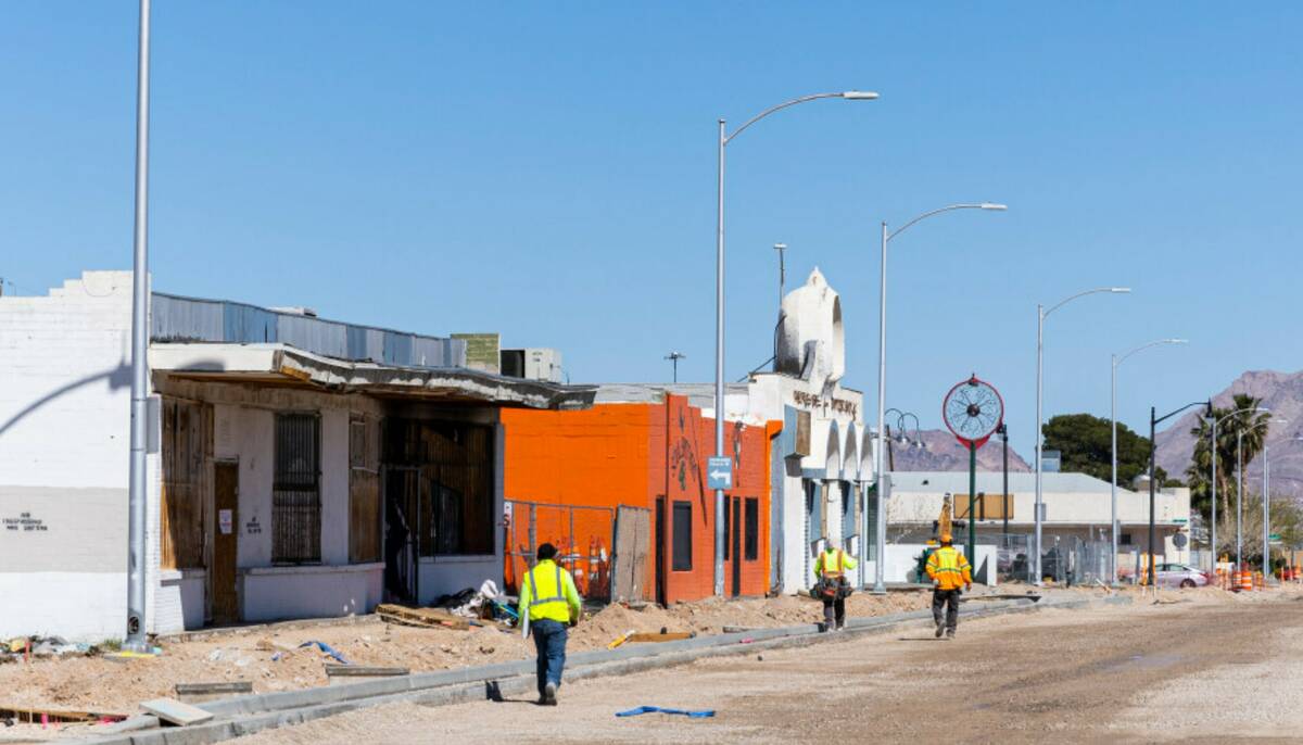 Road workers walk along Jackson Avenue near a lot, out of frame, where a 60-story mixed-use res ...