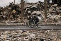 Men ride bicycles by a destroyed apartment building in Borodyanka, Ukraine, Wednesday, April 6, ...