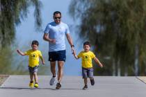 Eddie Saiz, of Henderson, runs with his three-year-old twin sons Aaron, left, and Oscar, right, ...
