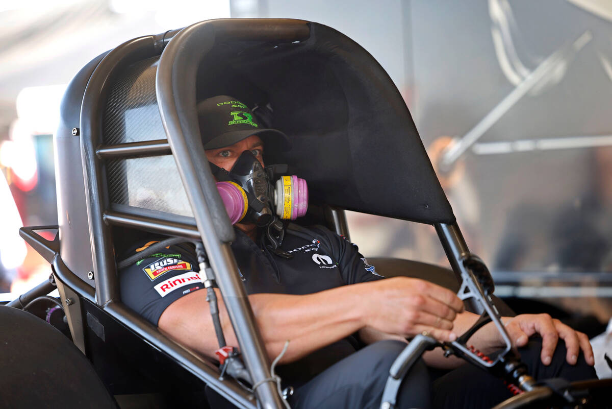 NHRA driver Matt Hagan, left, sits in his funny car as his crew checks the car before the first ...