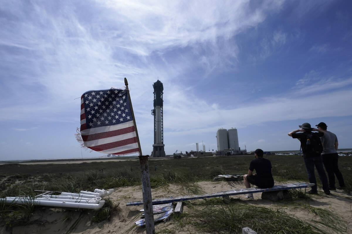 Onlookers watch as SpaceX's Starship, the world's biggest and most powerful rocket, stands read ...