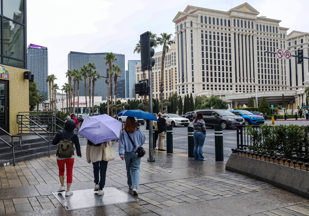 Pedestrians walk the Strip with umbrellas in Las Vegas, Tuesday, March 14, 2023. An incoming at ...