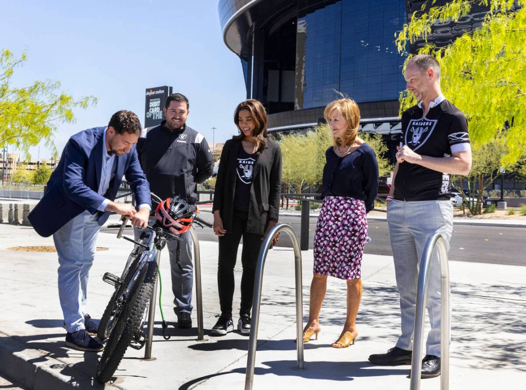 Clark County commissioner Michael Naft locks a bike on a rack as Raiders President Sandra Dougl ...