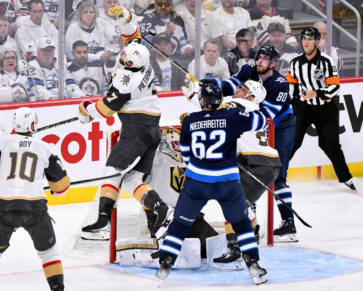Vegas Golden Knights' Alex Pietrangelo (7) and Winnipeg Jets' Pierre-Luc Dubois (80) reach for ...