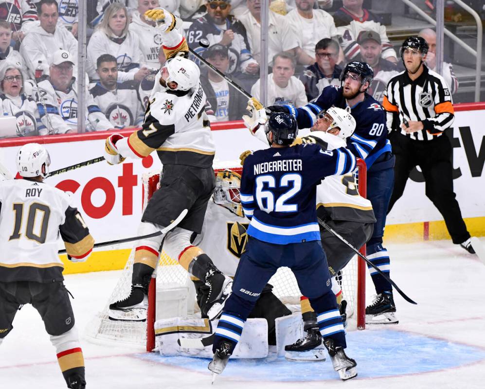 Vegas Golden Knights' Alex Pietrangelo (7) and Winnipeg Jets' Pierre-Luc Dubois (80) reach for ...