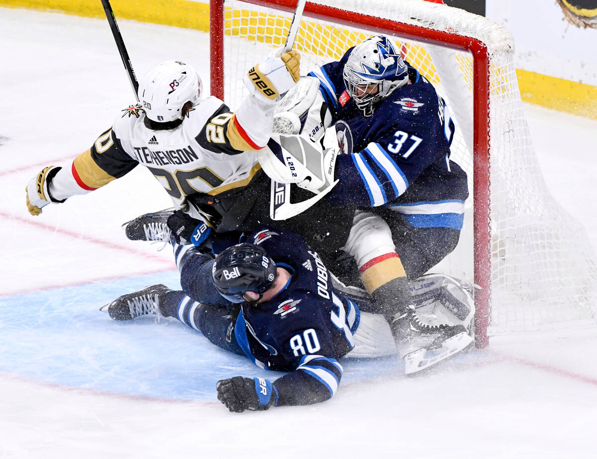 Vegas Golden Knights' Chandler Stephenson (20) collides with Winnipeg Jets goaltender Connor He ...