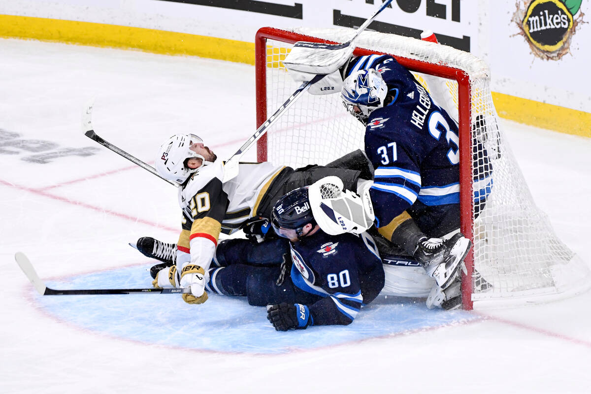 Vegas Golden Knights' Chandler Stephenson (20) collides with Winnipeg Jets goaltender Connor He ...