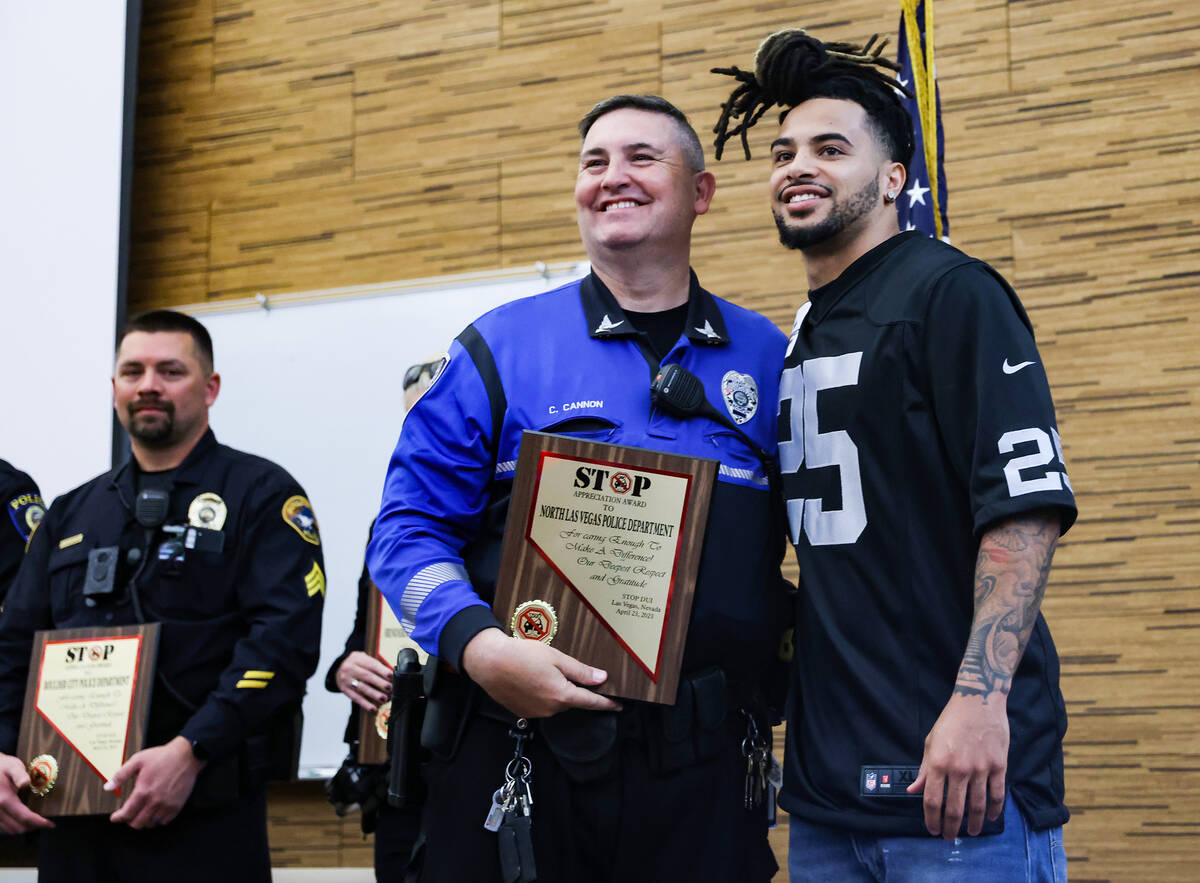 North Las Vegas Police Officer Chris Cannon, left, poses for a photo with Raiders safety Trevon ...