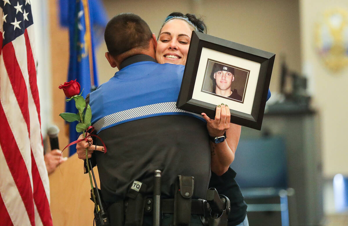 North Las Vegas Police Officer Andy Navarro hugs Sara Spenia, holding a photo of her brother Fr ...