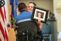 North Las Vegas Police Officer Andy Navarro hugs Sara Spenia, holding a photo of her brother Fr ...