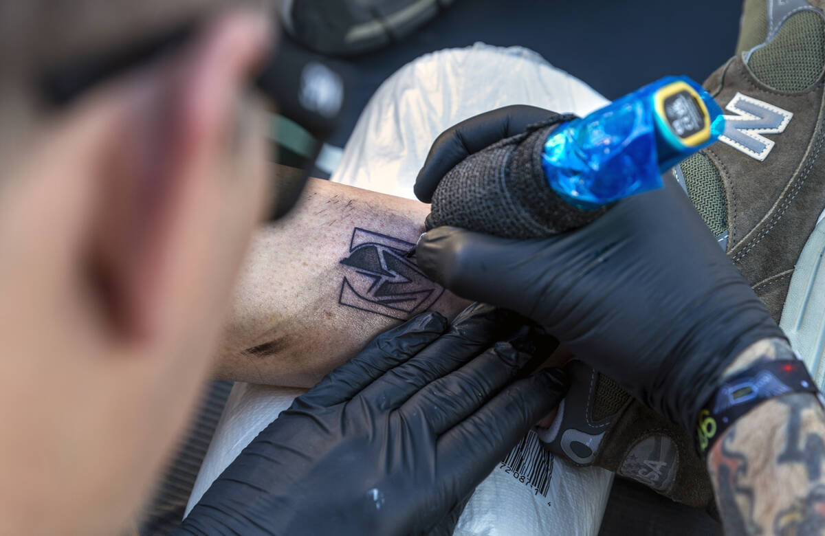 Tattoo artist Kapps with Revolt Tattoos works on a Golden Knights piece on the ankle of fan Wal ...