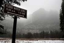 Yosemite Falls is covered behind a sign marking the water level of the 1997 flood in Yosemite N ...
