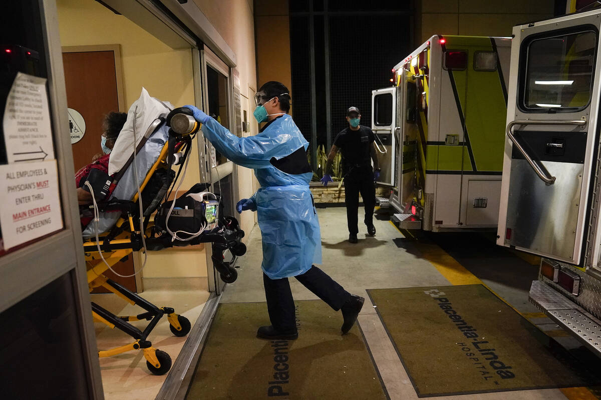 In this Jan. 8, 2021, file photo, emergency medical technician Thomas Hoang, 29, pushes a gurne ...