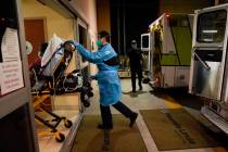 In this Jan. 8, 2021, file photo, emergency medical technician Thomas Hoang, 29, pushes a gurne ...