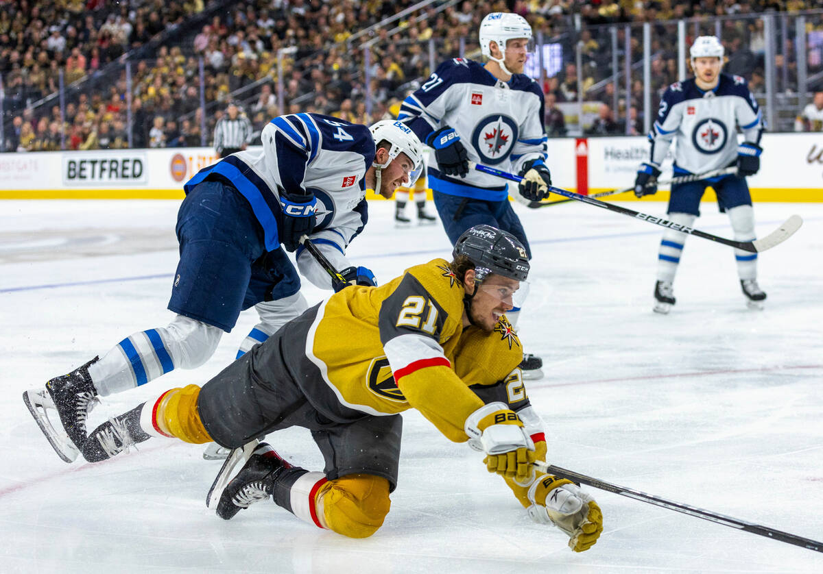 Golden Knights center Brett Howden (21) is taken down on a drive by Winnipeg Jets defenseman Dy ...