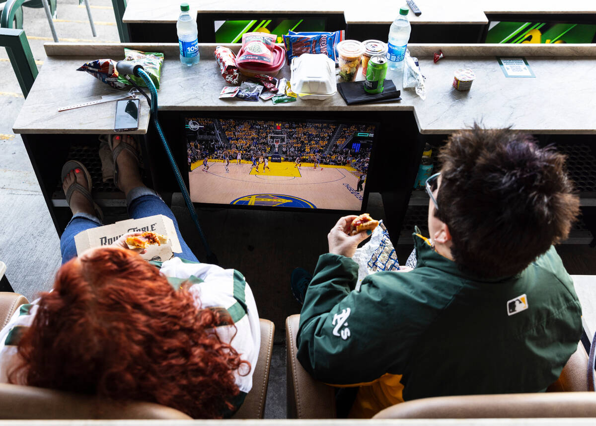 The Oakland A's fans Jennifer Riback, left, and Robin Chinn watch a televised basketball game b ...