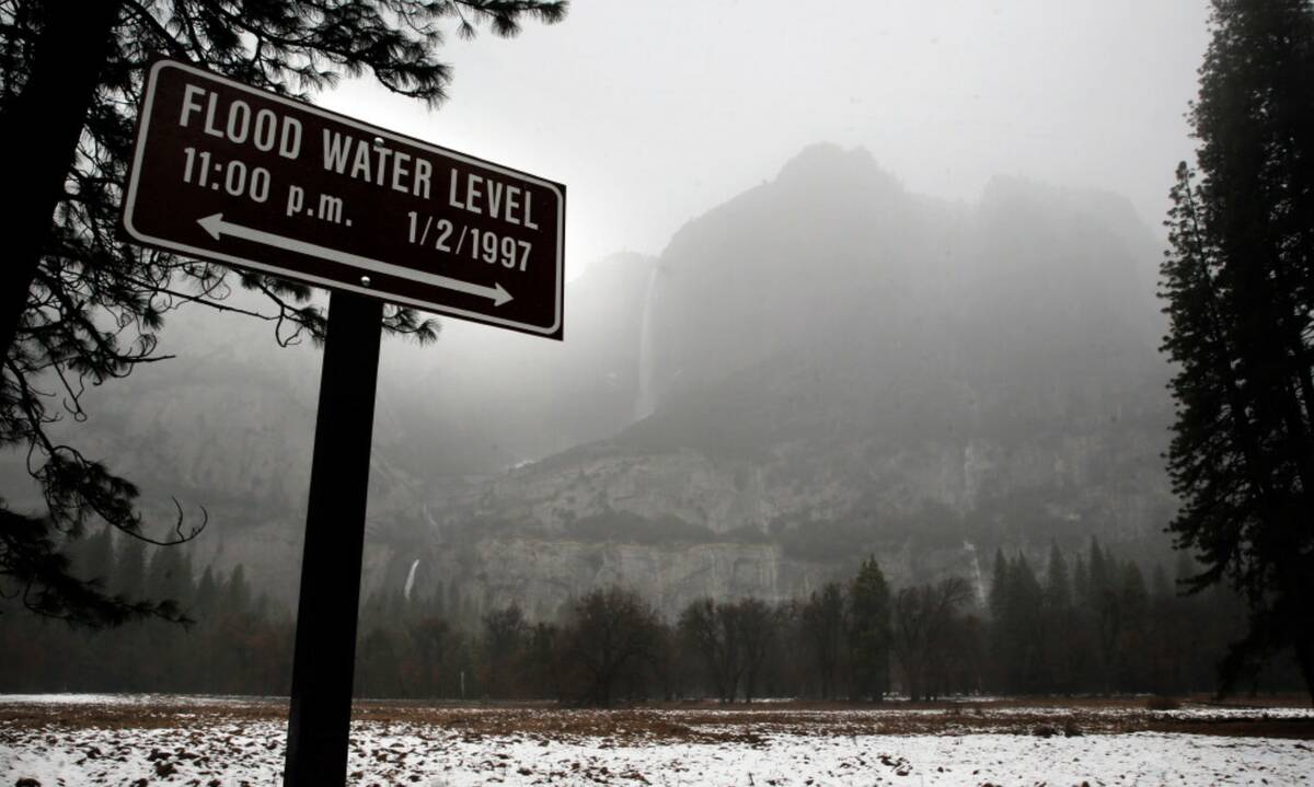 Yosemite Falls is covered behind a sign marking the water level of the 1997 flood in Yosemite N ...